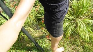 Refreshing & wetting t-shirt and black shorts in hose in the garden...