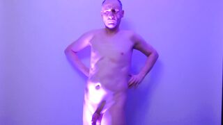 Man posing naked in a blue light his uncut cock shaved and flaccid shows off his nude body